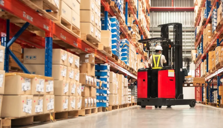 Worker in forklift-truck loading packed goods