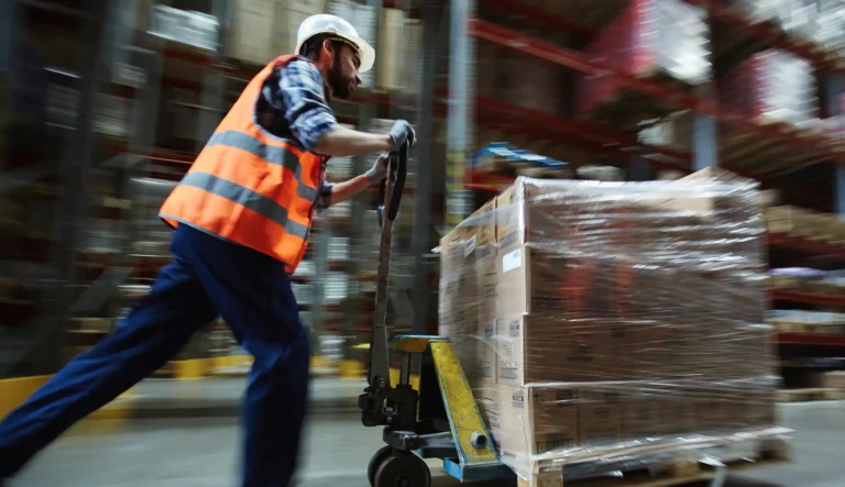 Man in uniform pushing cargo on forklift